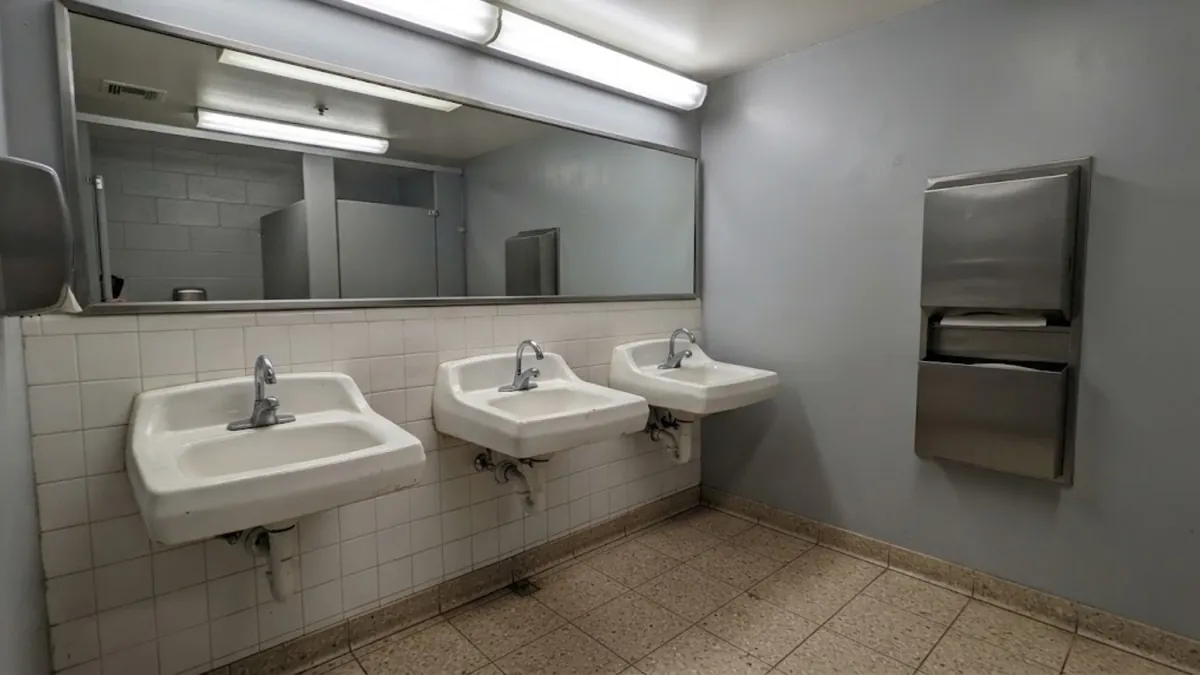 Floor drain and stainless hand sink in an empty commercial kitchen for commercial plumbing in Mission Viejo